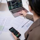 pexels-photo-7693229-7693229 A business professional analyzing stock charts on a laptop and smartphone at the office.