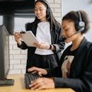 pexels-photo-8867475-8867475 Two women in a call center working with headsets and computers, focusing on customer support.